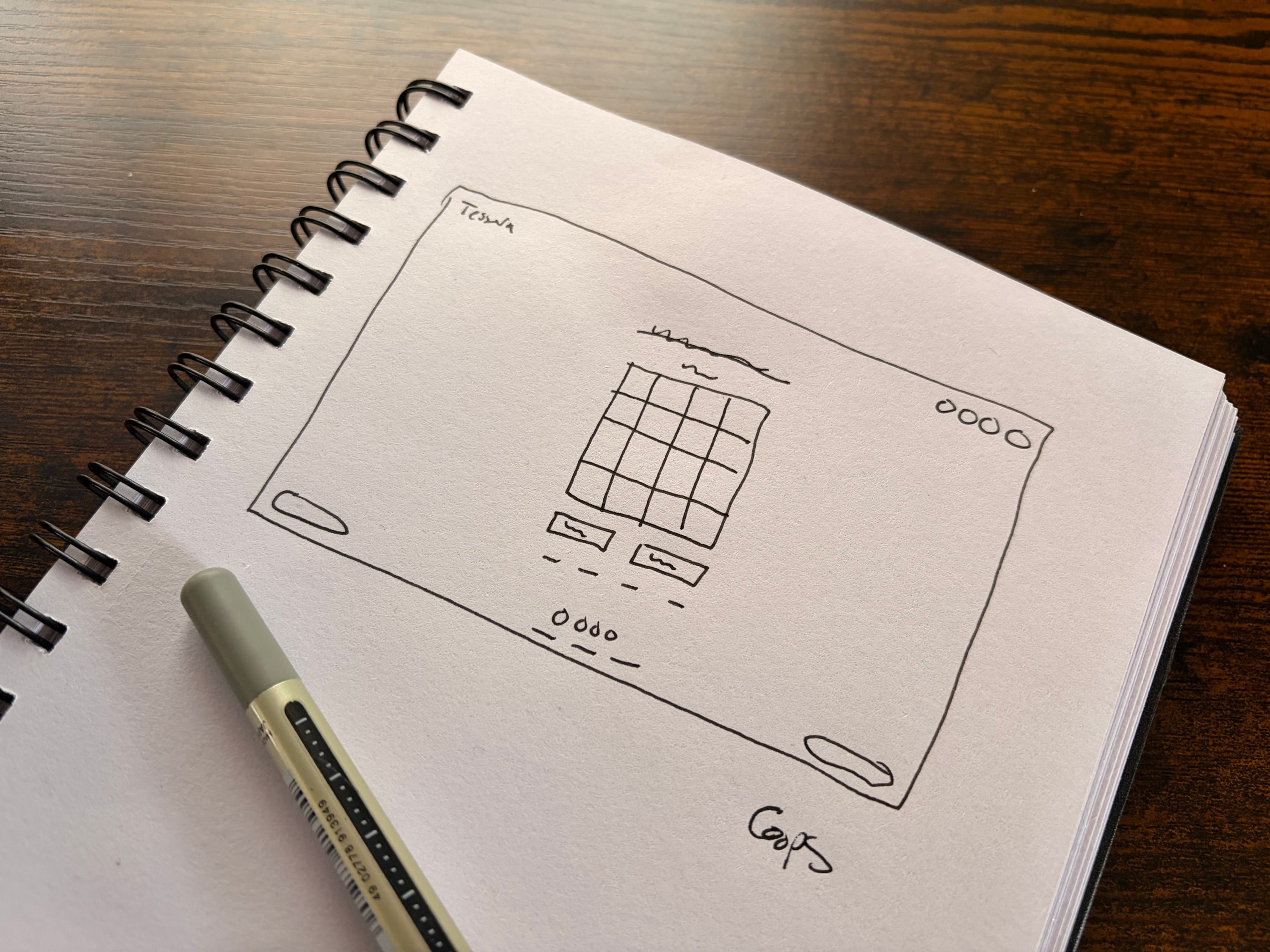 A hand-drawn wireframe of the Tessera screen in a spiral notebook: a 4x4 grid, a header, controls below it, and rough boxes for buttons.